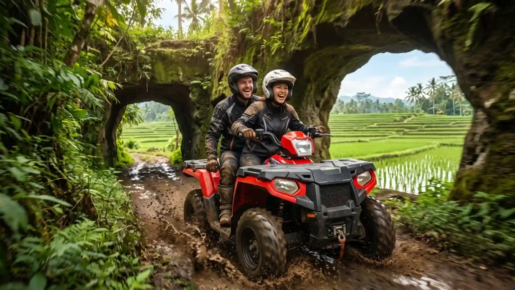 Two riders on an ATV quad bike coming out of a rock tunnel beside rice fields in Bali