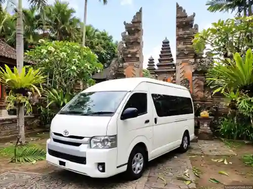 White Toyota Hiace minibus in front of a Balinese gate