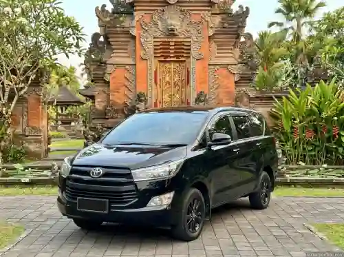 Black Toyota Innova private car in front of a Balinese gate